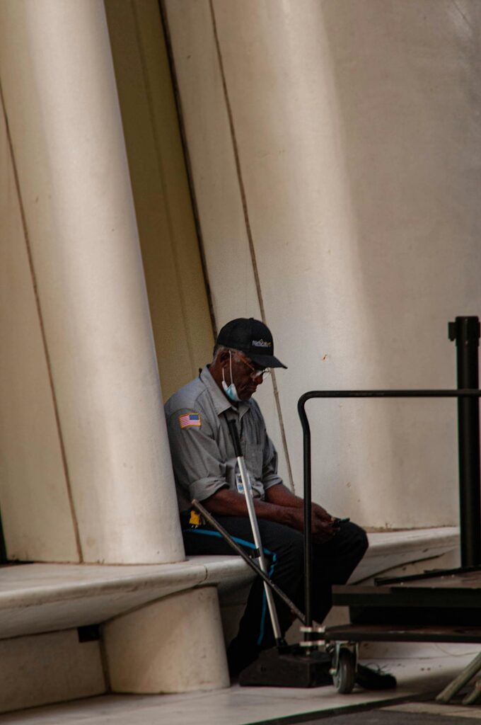 pexels-photo-13008231-13008231 African American security guard sitting and resting during a break outside a building in New York.
